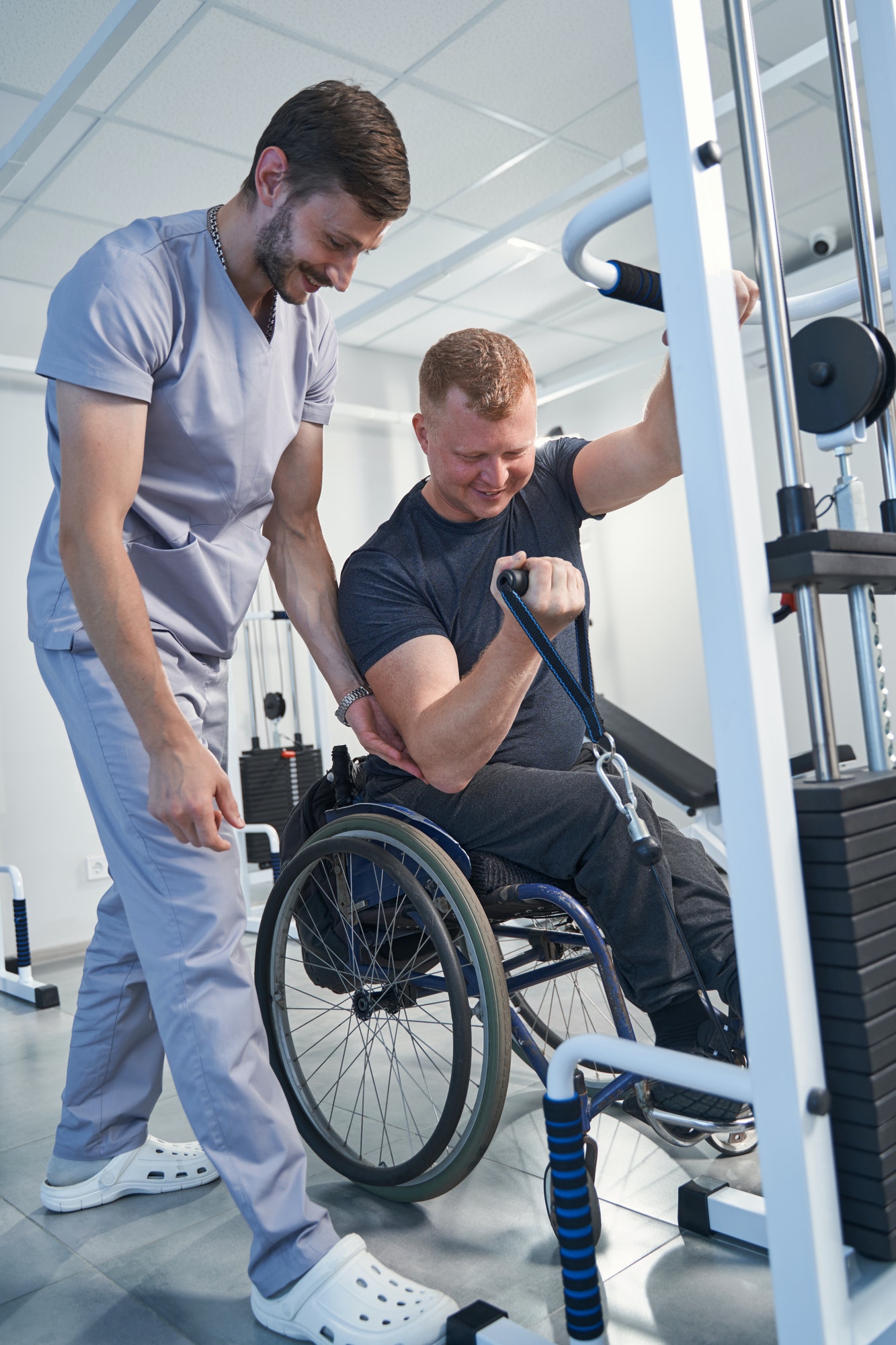 Happy therapist treat wheelchair patient. Man with sport injury